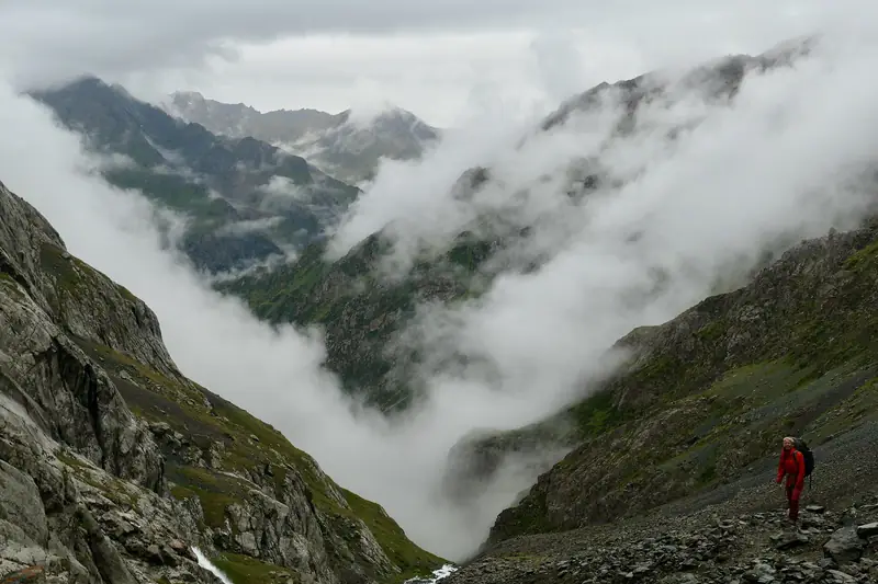 Nuages dans une gorge rocheuse escarpée, la figure d'un touriste ci-dessous