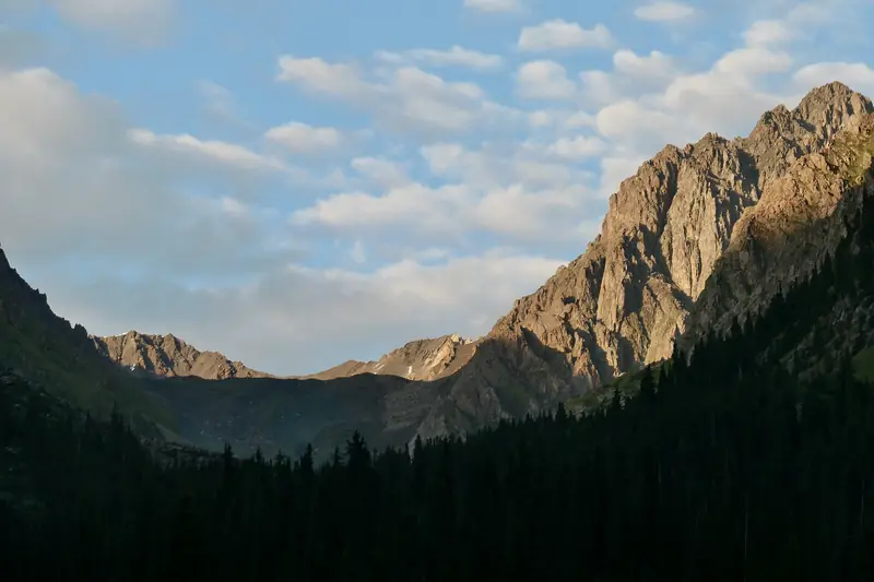 Soleil du soir sur une crête rocheuse au-dessus d'une forêt sombre