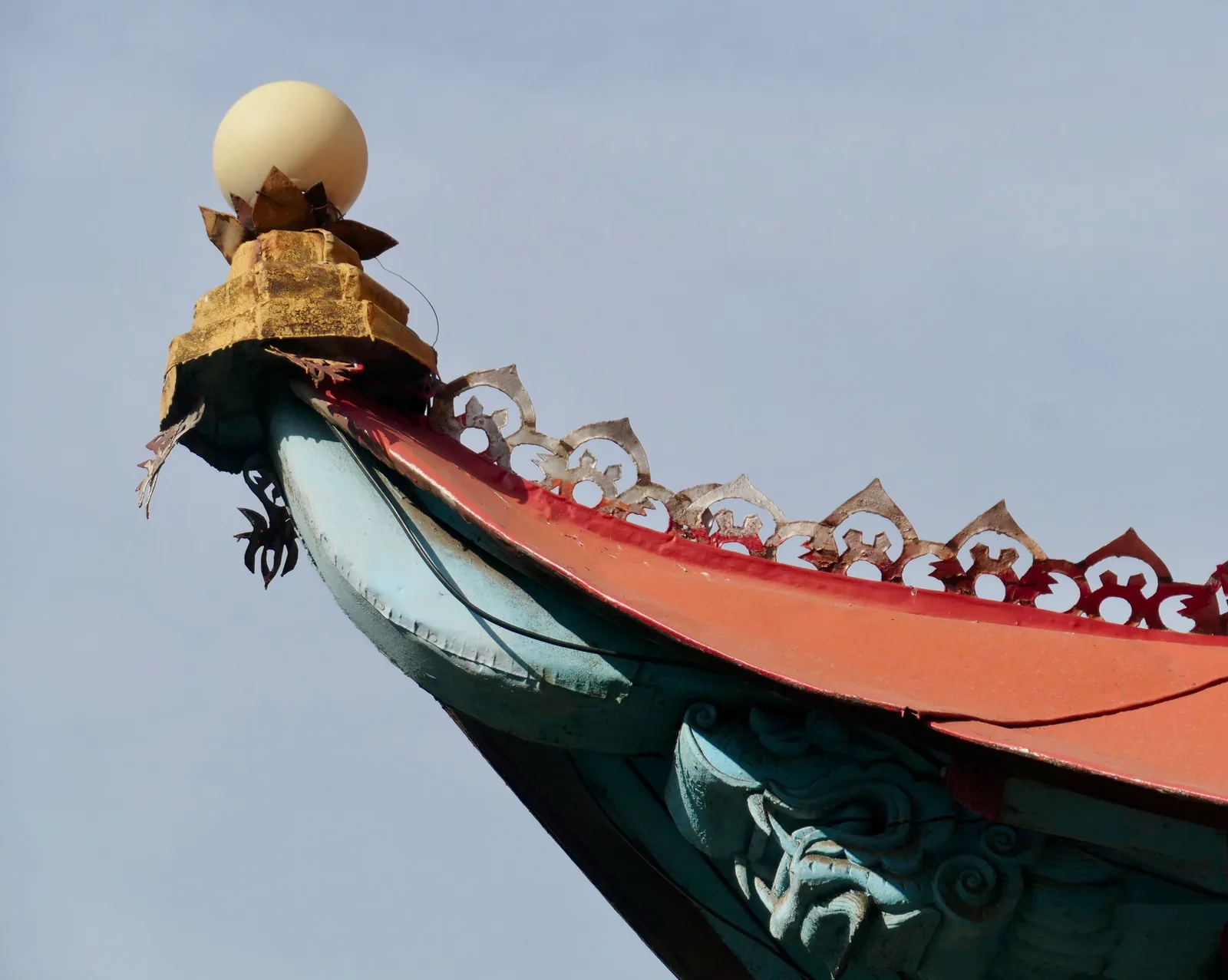 Geschnitzter Drachenkopf am aufgebogenen Ende eines Eckbalkens, darüber eine goldene Spitze