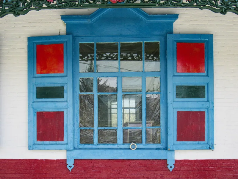 Blaues Fenster mit roten Einsätzen in einer weißen Wand