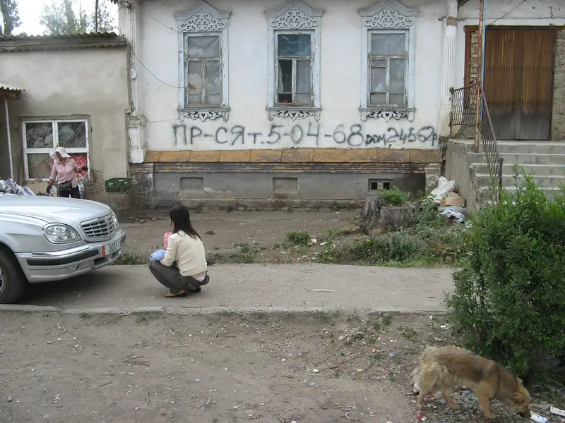 Casa antigua con molduras blancas talladas, una acera y un coche delante