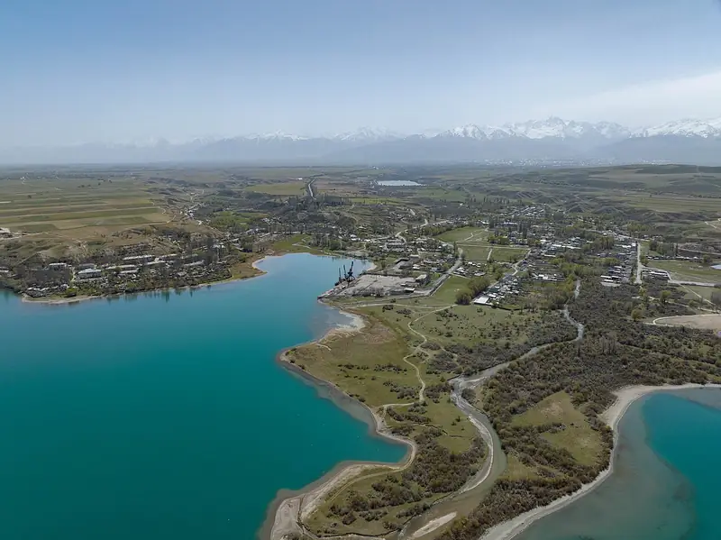 Desde arriba: una bahía turquesa, un pueblo en un cabo, campos, montañas a lo lejos