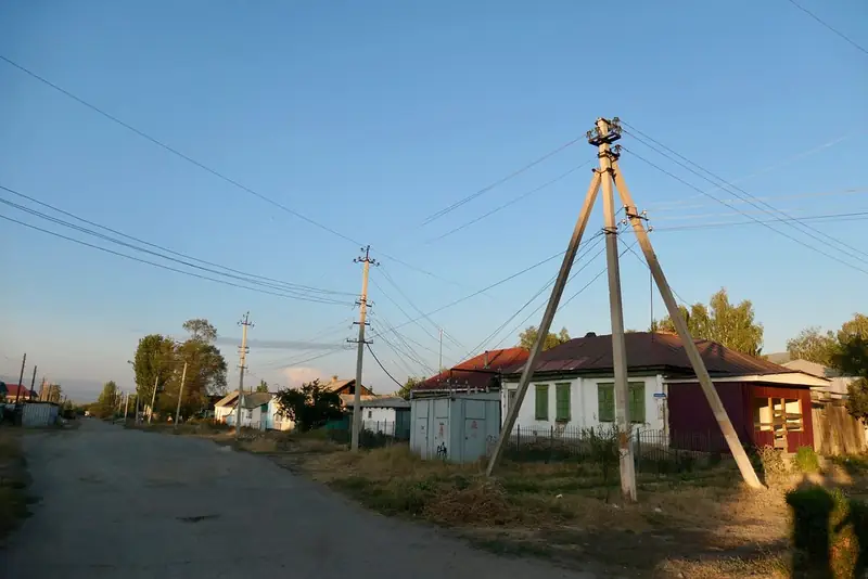 Calle de tierra, casas de un piso y pilares a la luz del atardecer