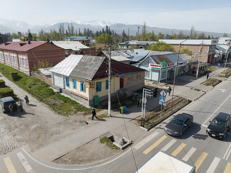 Desde arriba: casas antiguas de una planta en una esquina, detrás la ciudad y montañas nevadas