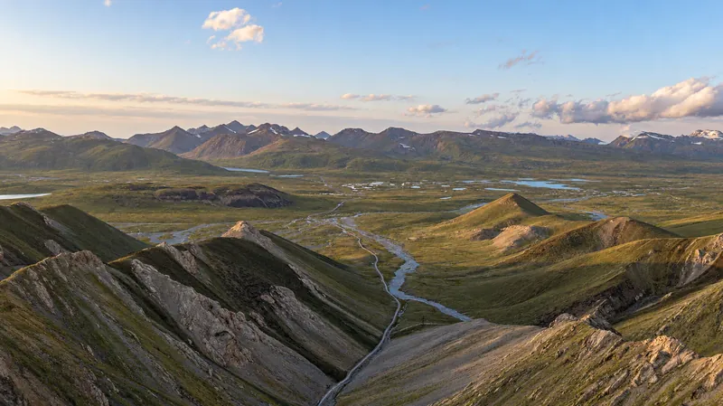 La vallée d’Arabel dans la lumière chaude d’un soir d’été, avec des chenaux et des chaînes de haute montagne.