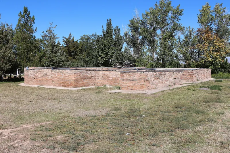 Basse fondamenta rettangolari in mattoni di antichi edifici si trovano tra l’erba dell’antico abitato.