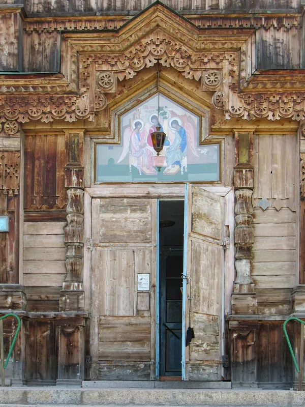Die Holztüren der Kirche sind mit geschnitzten Details umrahmt und über dem Eingang ist eine Ikone angebracht.