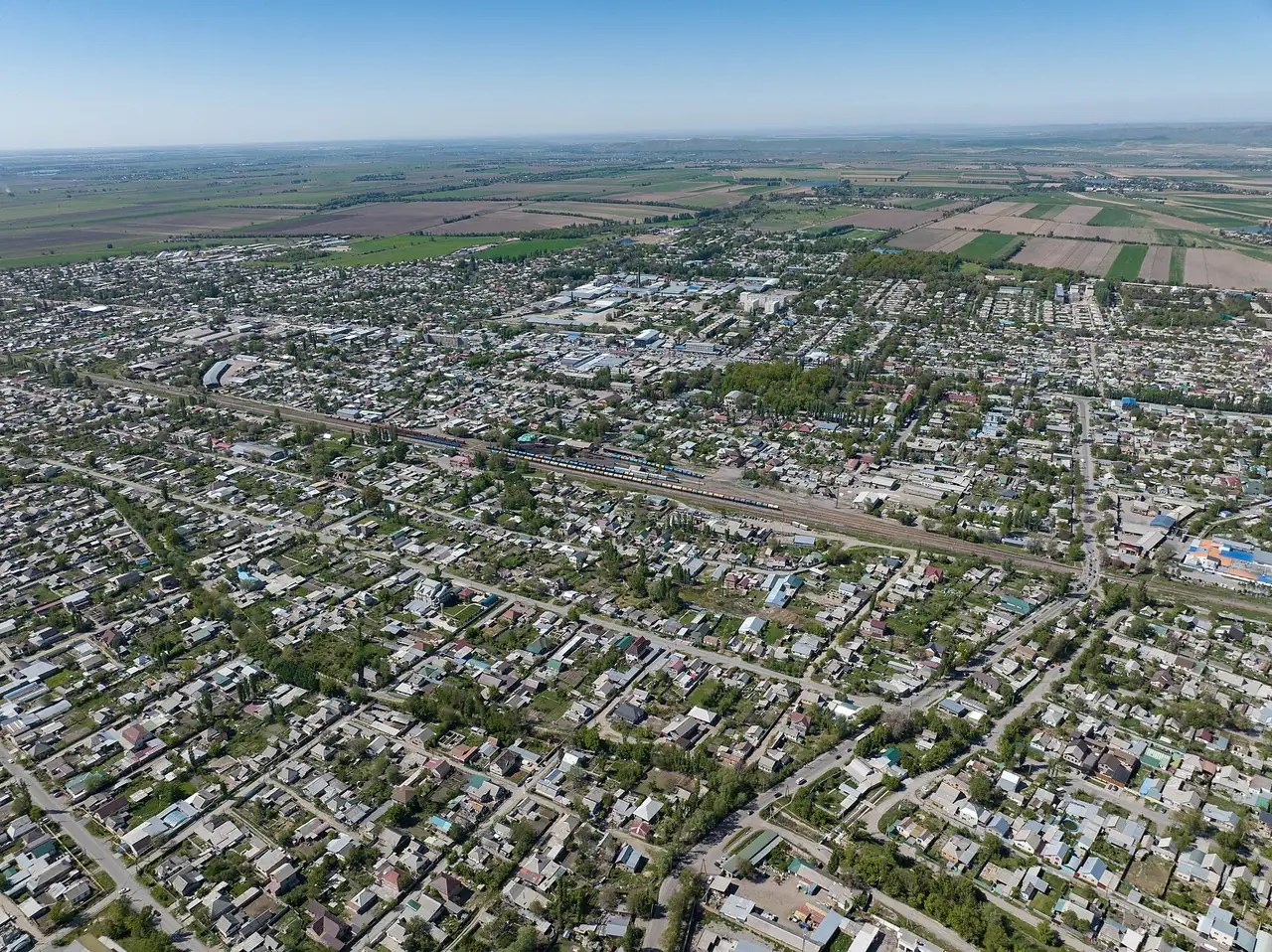 Viertel von Kant mit niedrigen Häusern und grünen Grundstücken; hinter der Stadt sieht man Felder.