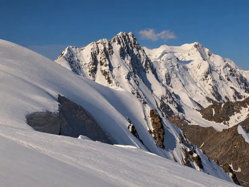 Herbstlicht auf einem schneebedeckten Pik Karakol und abgerundeten Eisrücken.