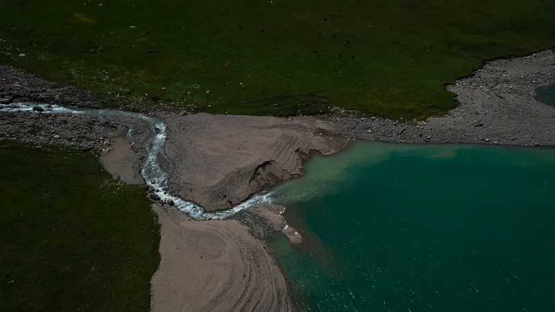 Bäche verzweigen sich in einem steinigen Delta und münden in das blaue Wasser eines Bergsees.