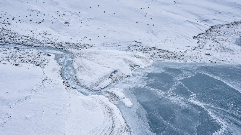Winteransicht von oben auf den zugefrorenen See Kolukok und das schneebedeckte Bachbett.