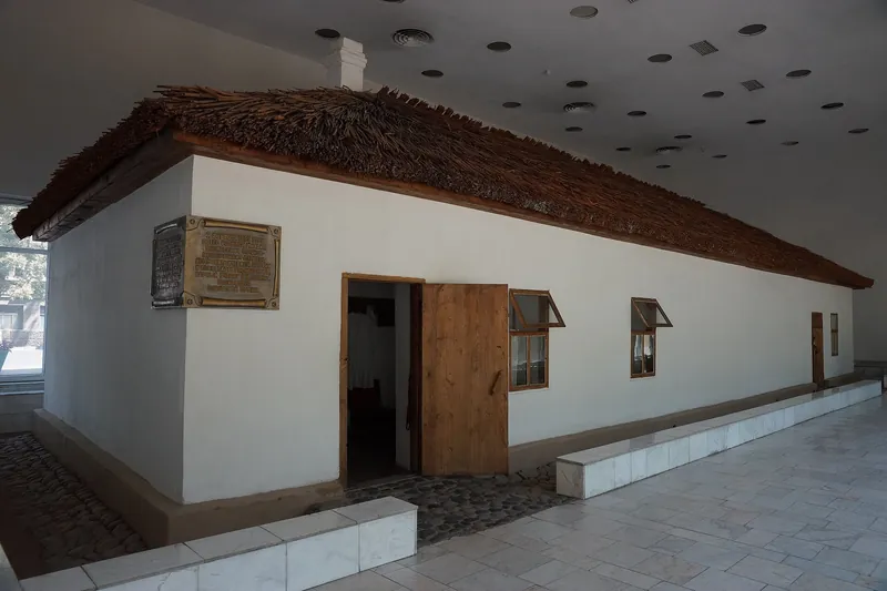 Gedung Putih di bawah atap ubin dilestarikan di dalam aula museum, dikelilingi oleh etalase dan platform.