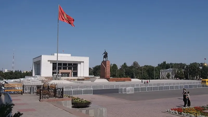 Bangunan museum berwarna putih berdiri di belakang alun-alun luas, tiang bendera dan monumen berkuda.