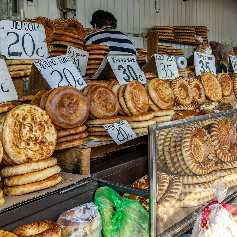 Runde Fladenbrote mit gemusterten Mitten in Reihen auf dem Stand unter handgeschriebenen Preisschildern.