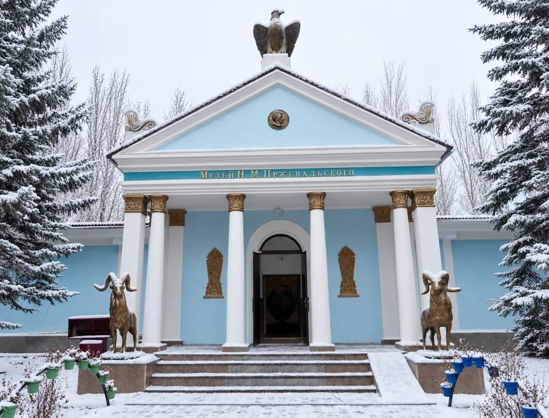Museo bianco con colonne azzurre e portico, con un ornamento scultoreo sopra l’ingresso; vista in inverno.