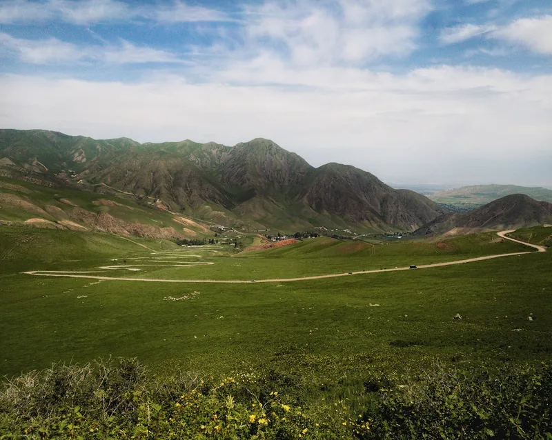 El valle de Chunkurchak, con una carretera entre las laderas de las estribaciones, a principios de mayo