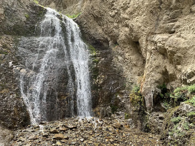 Иссык-Атинский водопад в ущелье летом, вода падает со скального уступа