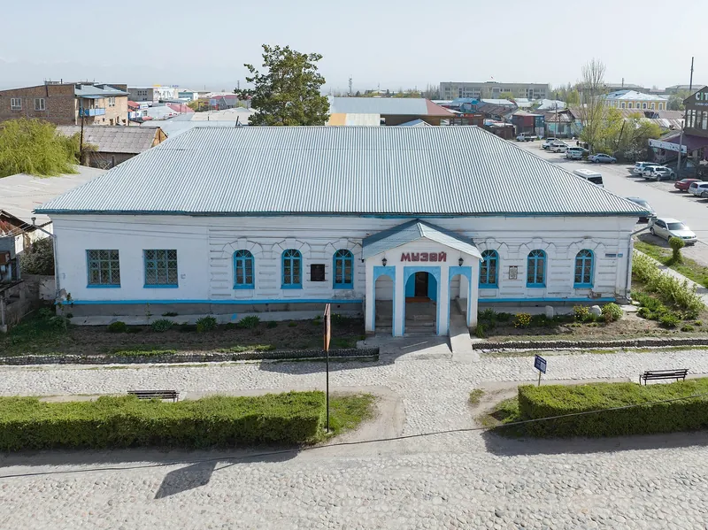 Un museo blanco de un piso con techo gris, puertas azules y pasillos al frente.