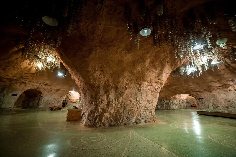 La bóveda de piedra de la sala del museo se apoya en un pilar macizo, rodeado de vitrinas y lámparas de araña.