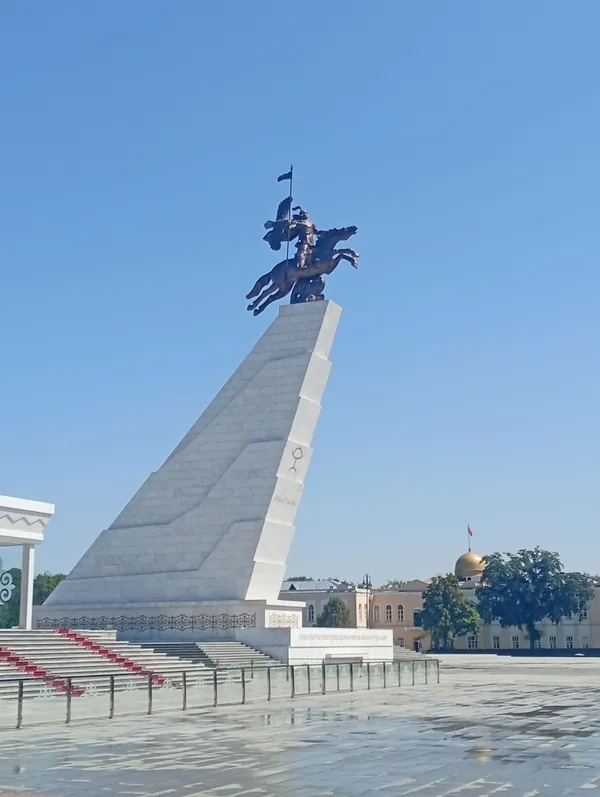 Una statua equestre su un alto piedistallo chiaro, con gradini e recinzione alla base.